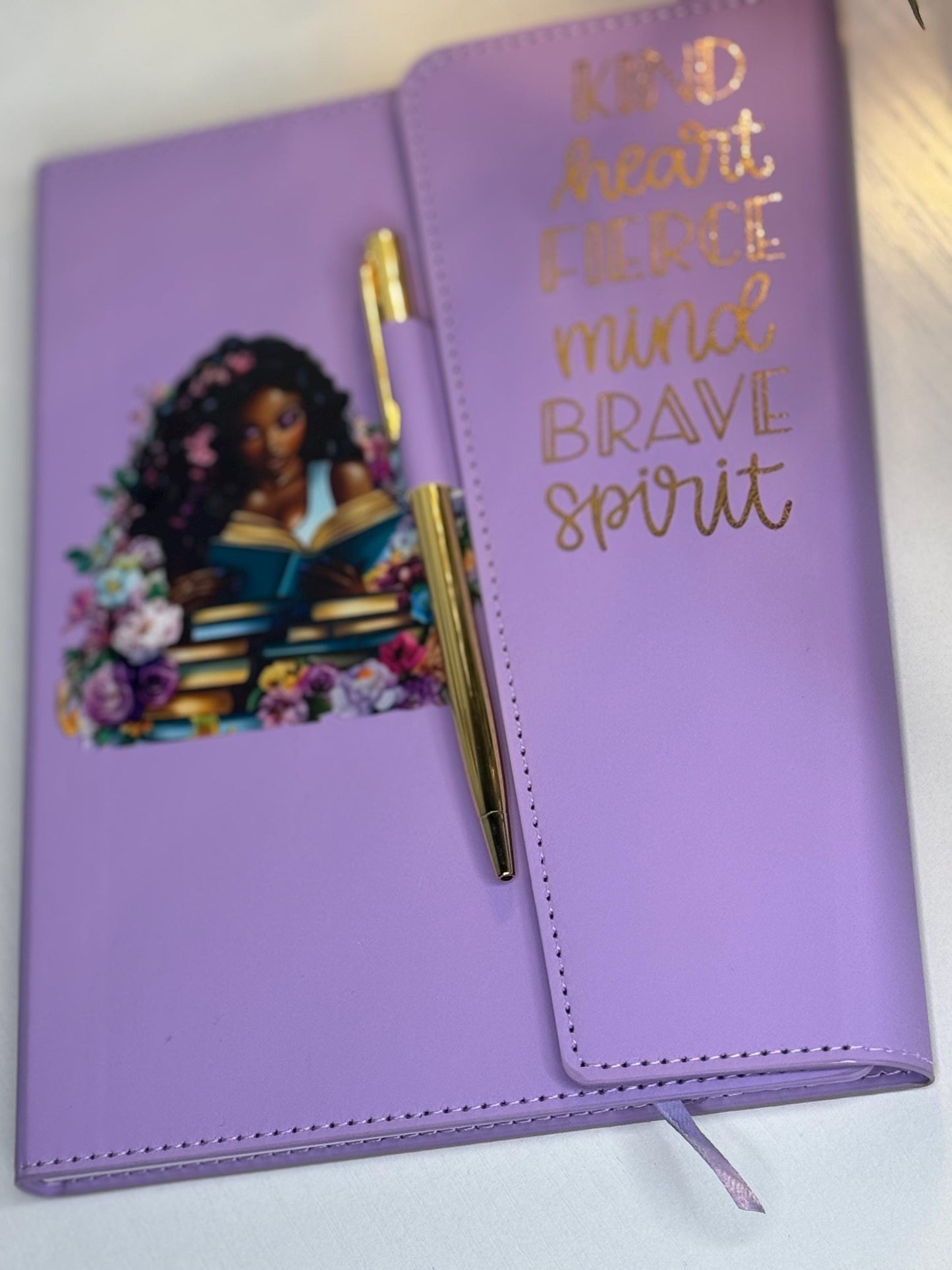 Purple affirmation journal featuring a black woman illustration with floral details, paired with a gold pen. This self care notebook is designed for daily journaling, mental health, and personal growth.